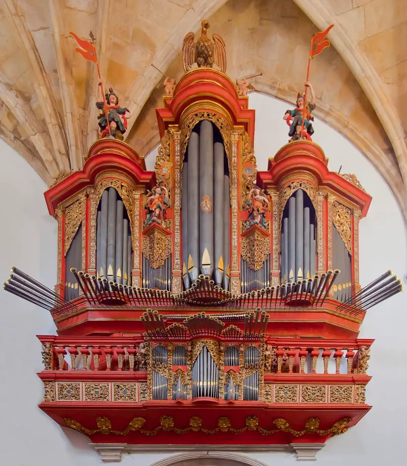 An ornate baroque organ in red and gold with rows of silver pipes