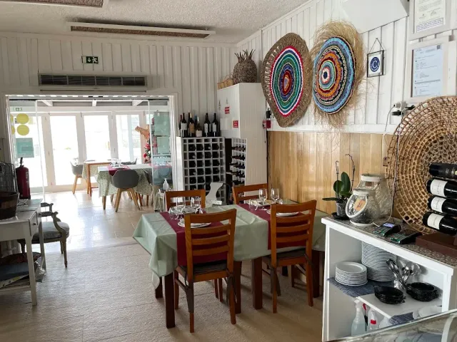 A white room with colourful woven mats on the wall and tables in green cloths