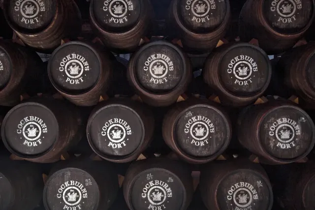Dark wine barrels stacked one above the other with white emblems on their faces