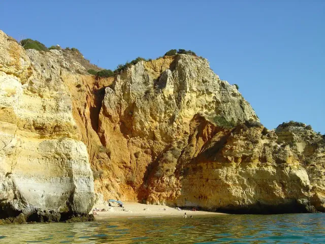 Honey coloured cliffs with wooden steps down to clear green water