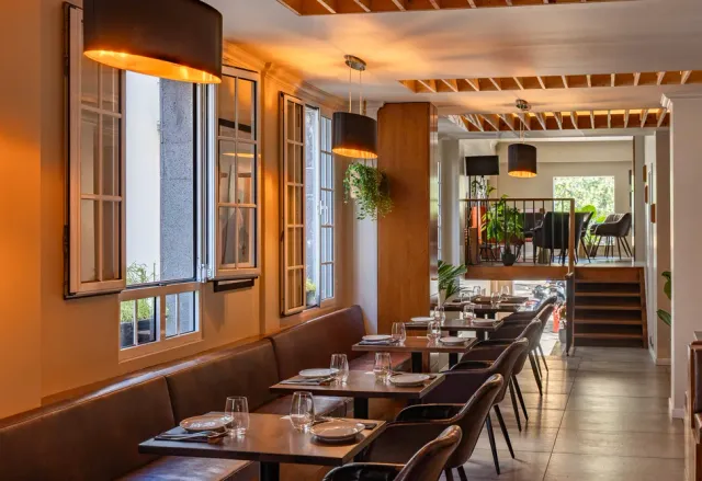 A warm room with a brown leather bench, wooden tables and open wooden windows