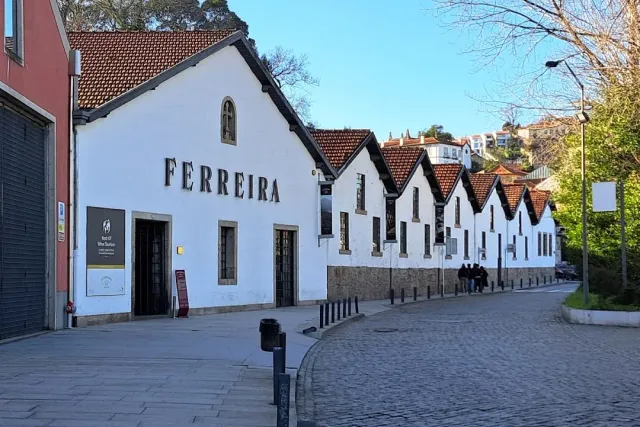 A row of white warehouses with tiled roofs and the wine house name in large letters on the facade