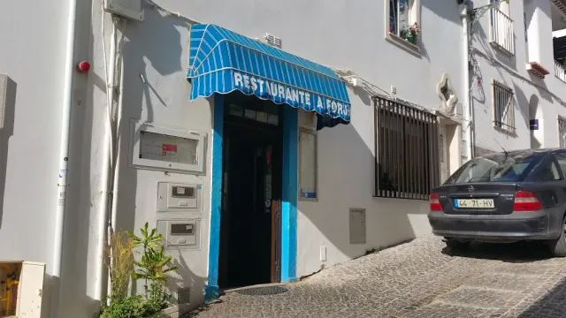 A blue entrance with a striped awning on a narrow paved street, and a car parked beside it