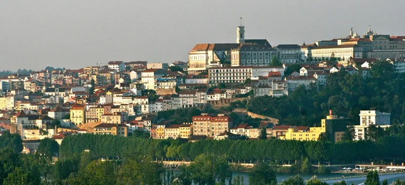 A hilltop town in golden light, topped by a long stone building with a clock tower