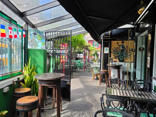A covered passage with high stools, barrel tables and flags on the wall