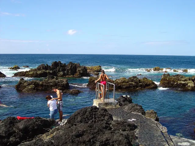 Water pools between jagged black lava rocks facing the open sea