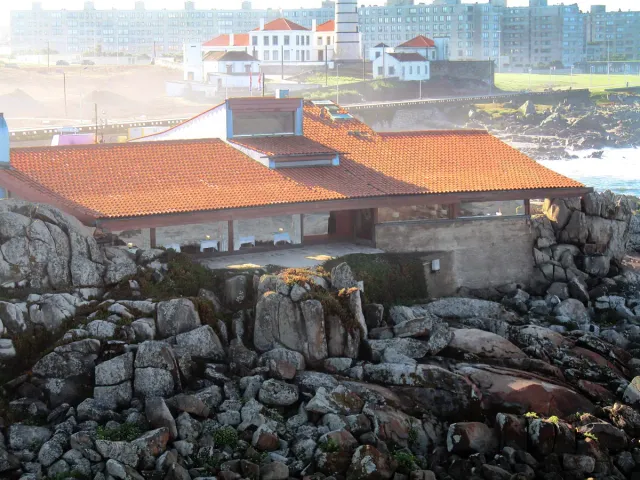 A low concrete and tiled roof building on coastal rocks facing the sea