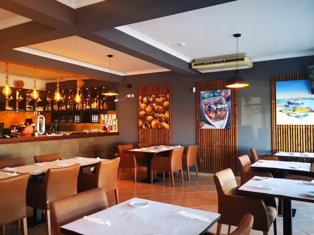A room with hanging lamps, boat paintings on wooden panels and set tables