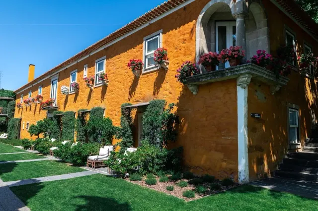 An orange manor house with geranium pots at the windows and a green lawn