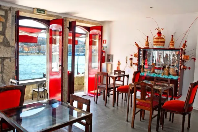 A room with red chairs and open red doors onto a view of the river and the opposite bank