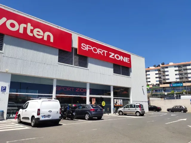 A commercial building with red chain store signs and a car park facing apartment blocks