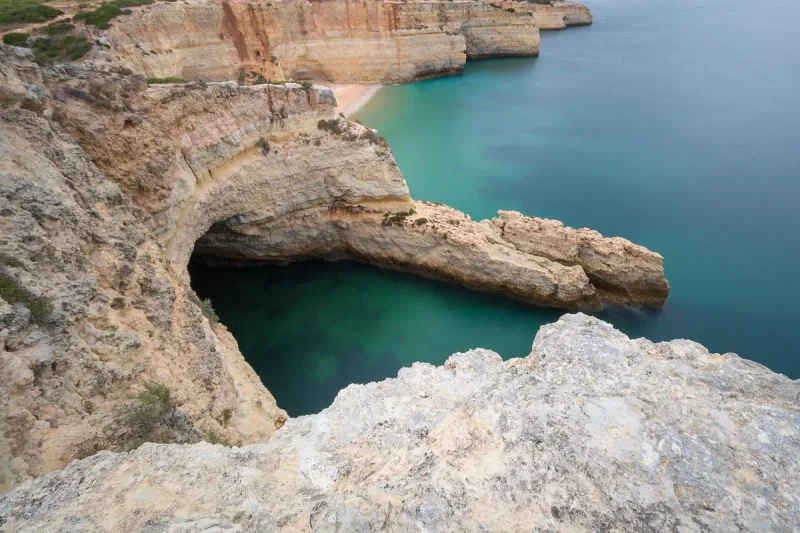 View from above into a hidden cove between limestone cliffs filled with deep turquoise water
