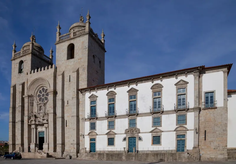 A fortress like cathedral front with a rose window and bell tower facing a square