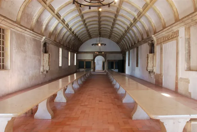 A long hall with a vaulted ceiling and two rows of benches and tables