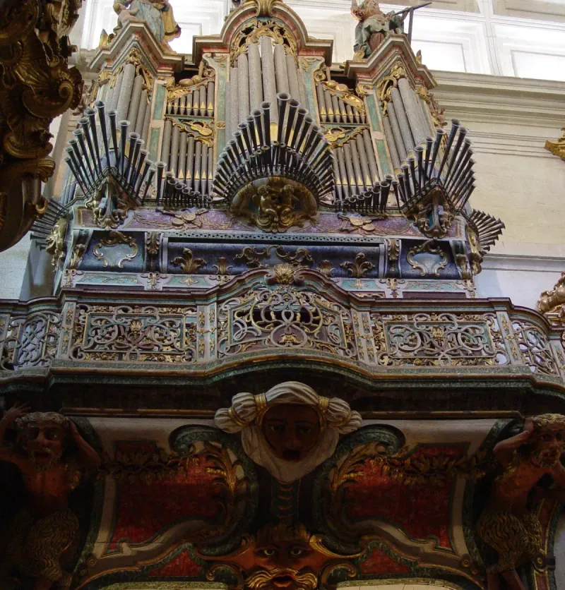 Gilded baroque organ with fanned ranks of pipes above carved figures bearing the gallery