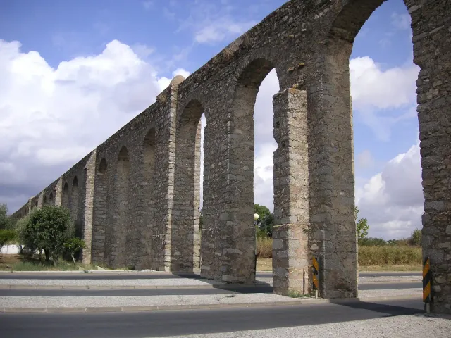 A row of tall stone arches running along a grass field