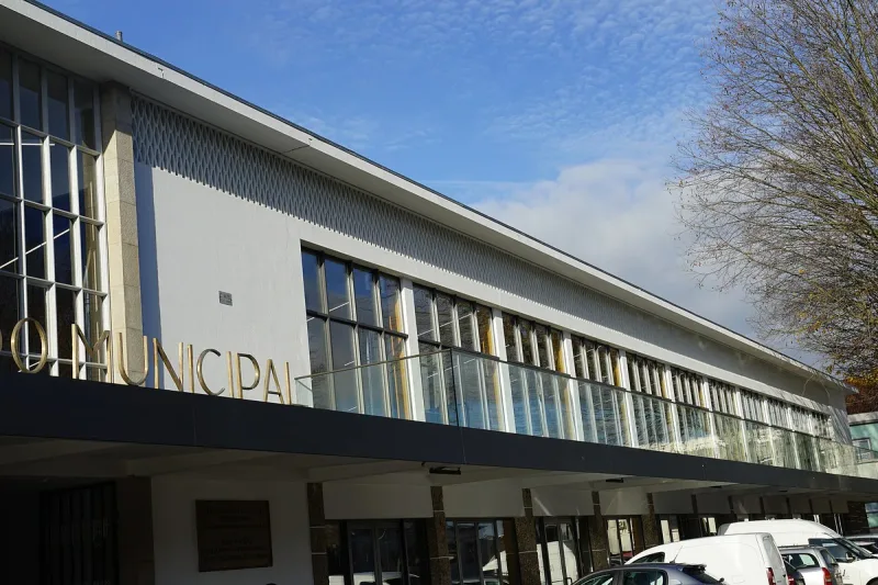 A modernist market building with a long glass front and gold lettering