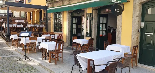 Tables in white cloths on a paved pavement in front of a yellow and green facade