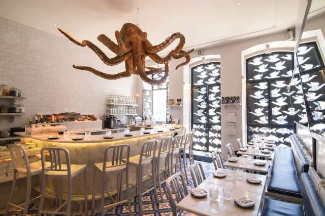A giant octopus sculpture hanging from the ceiling above a curved counter and white tables