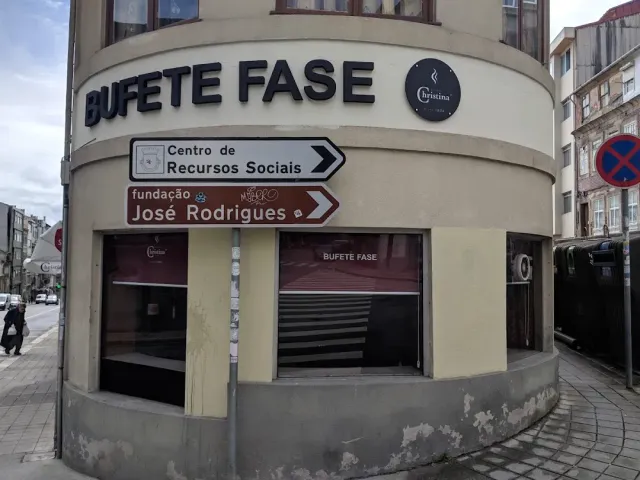 A building corner with raised letter signage above dark windows and direction signs