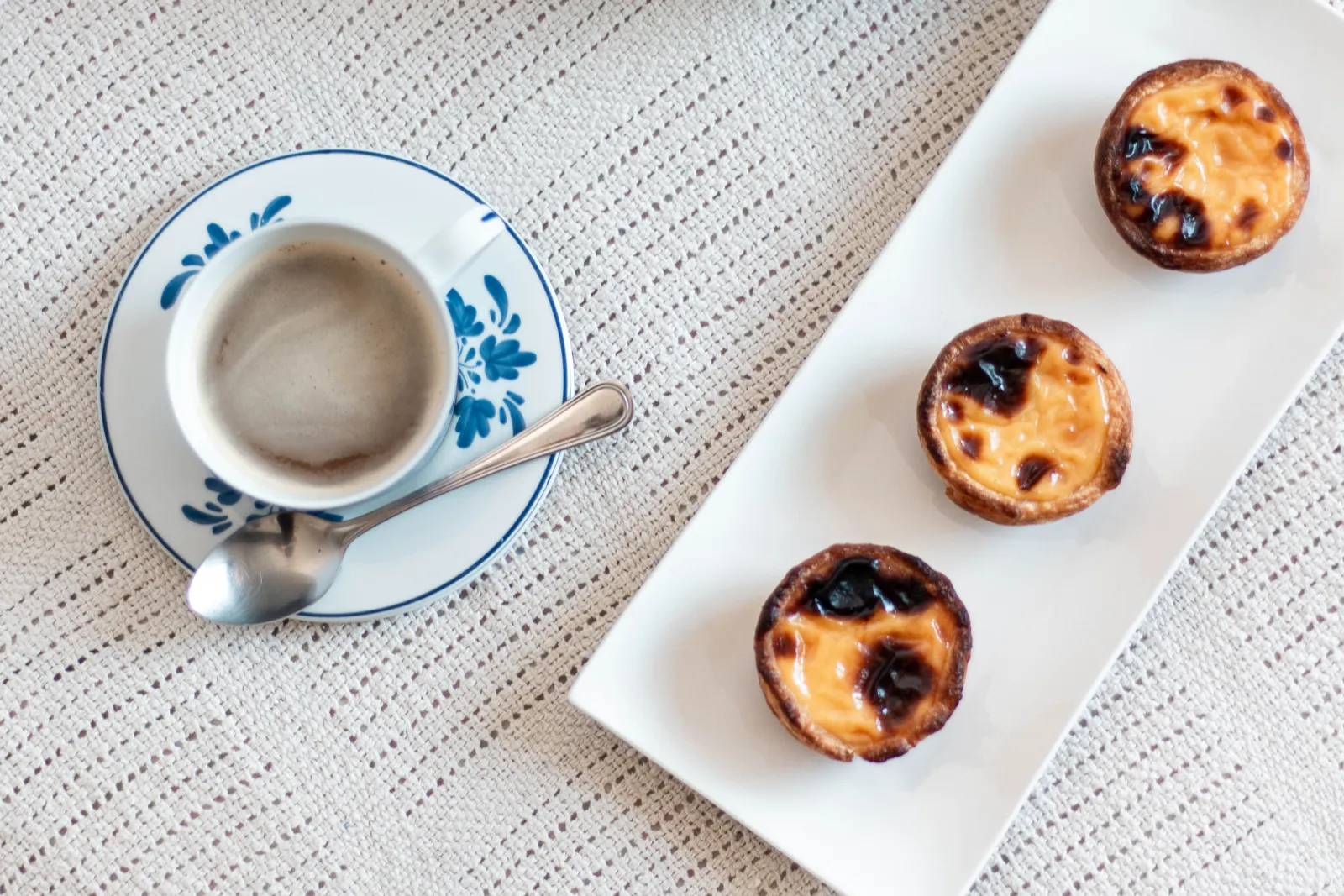 Small espresso cup and a custard tart on a saucer on a cafe counter in Portugal