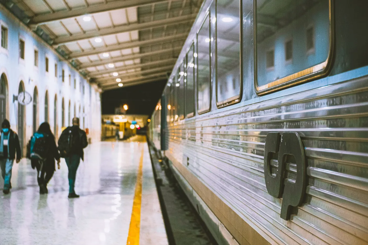 Passengers on the platform beside a CP train at Santa Apolonia station in Lisbon, Portugal