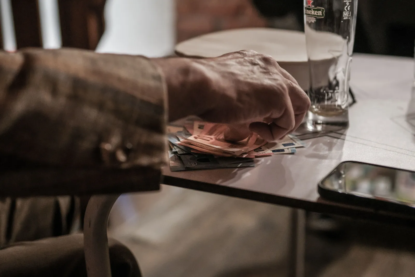 Traveller checking a phone with euro banknotes and coins on a cafe table in Portugal