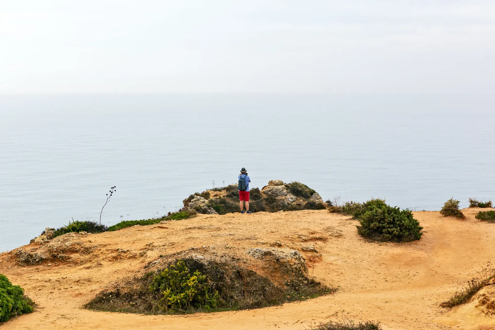 A sandy coastal path running along low orange cliffs above the Atlantic on Portugal's Rota Vicentina Fishermen's Trail