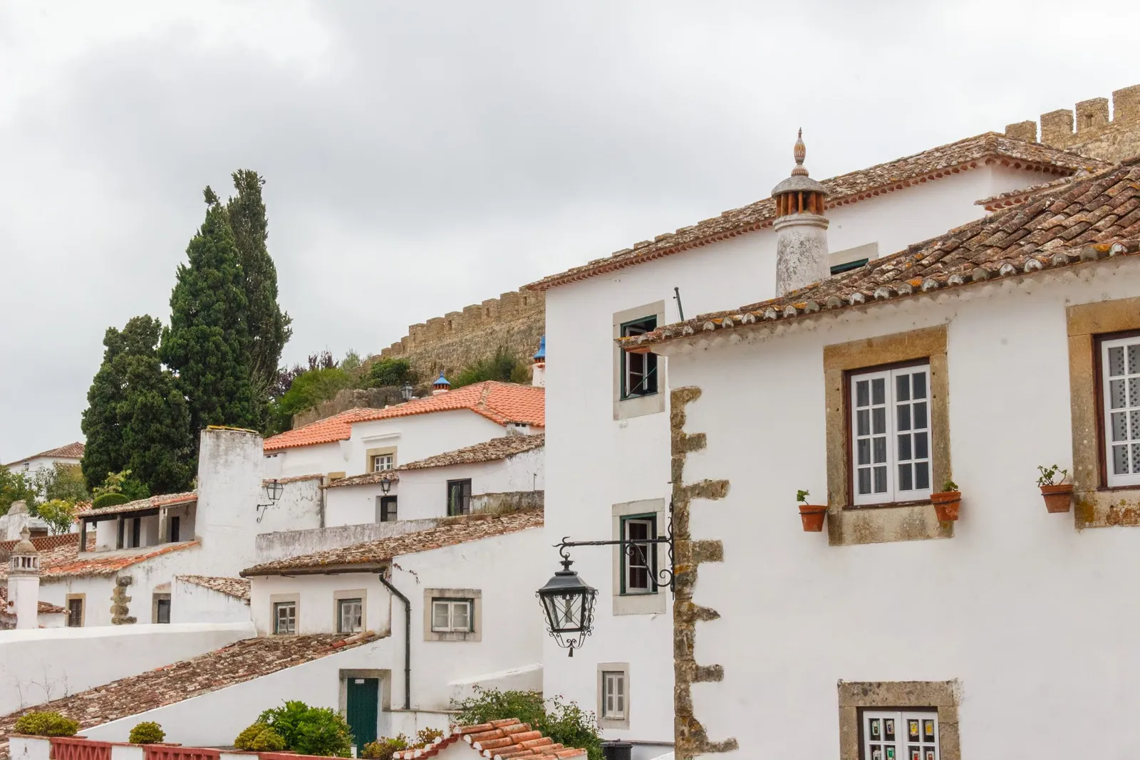 Whitewashed houses with terracotta roofs below the castle walls of a Portuguese hill town