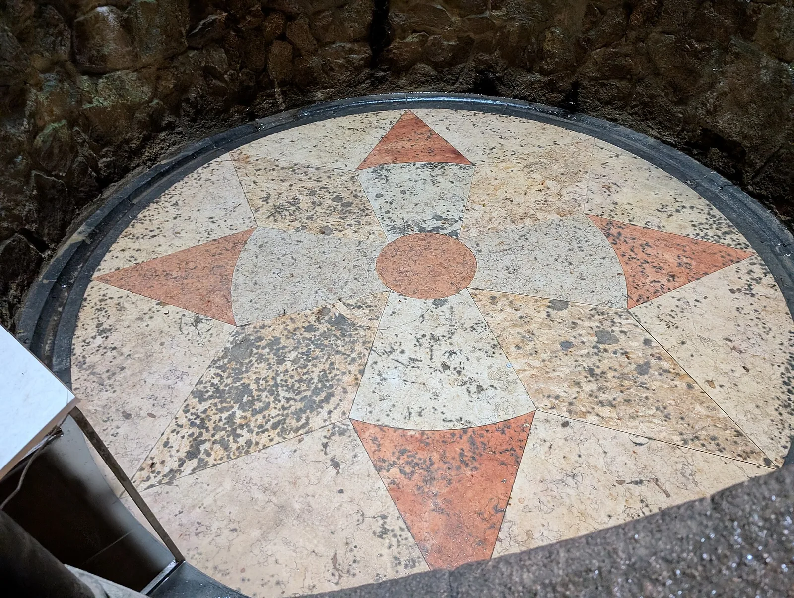 פסיפס הרצפה בצורת שושנת רוחות וצלב טמפלרים בתחתית באר החניכה בקווינטה דה רגאלייראה, סינטרה