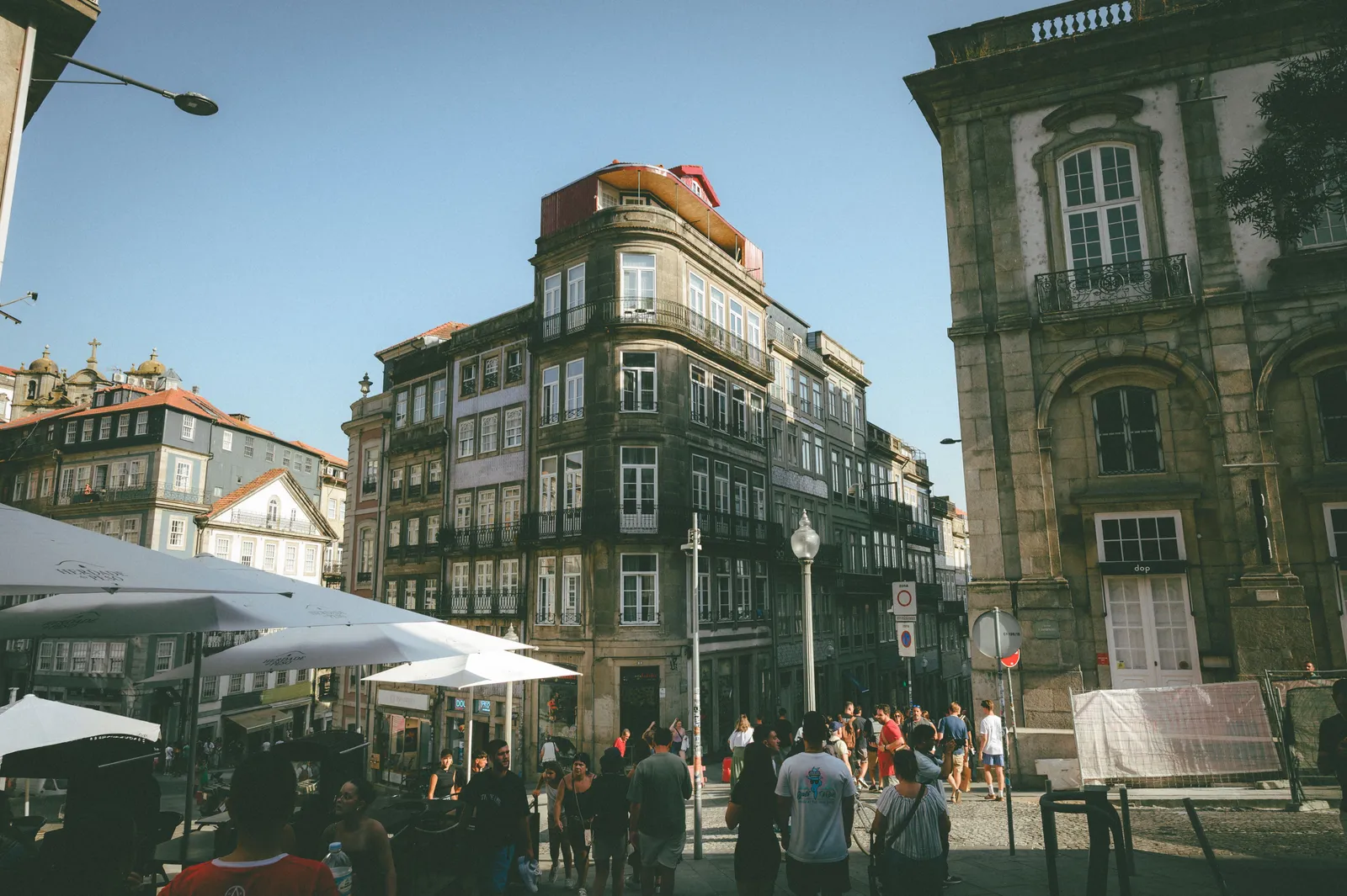 A wide street lined with cafes and pedestrians in central Porto, Portugal